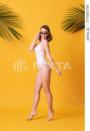 Happy young woman on yellow background dressed in swimwear. Happy young woman on yellow background dressed in swimwear. 77486784
