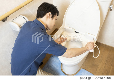 トイレの清掃をするハウスクリーニングの男性作業員の後ろ姿 77487106