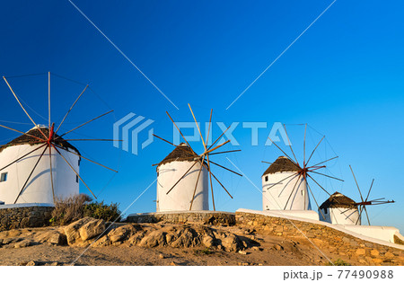 Famous tourist attraction of Mykonos, Cyclades, Greece. Four traditional whitewashed windmills by waterfront. Summer, travel destination, iconic view. Famous tourist attraction of Mykonos, Cyclades, Greece. Four traditional whitewashed windmills by waterfront. Summer, travel destination, iconic view. 77490988
