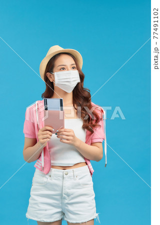 Woman wearing hygienic face mask to prevent contagious coronavirus, holding passport, safe resort tour Woman wearing hygienic face mask to prevent contagious coronavirus, holding passport, safe resort tour 77491102