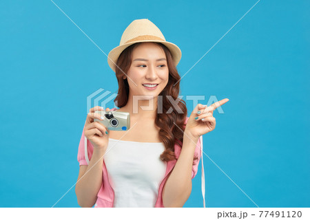 Attractive energetic Asian woman happily holding cemara isolated on blue studio background Attractive energetic Asian woman happily holding cemara isolated on blue studio background 77491120