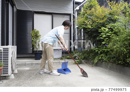 駐車場の掃き掃除をするハウスクリーニング の女性 駐車場の掃き掃除をするハウスクリーニング の女性 77499975