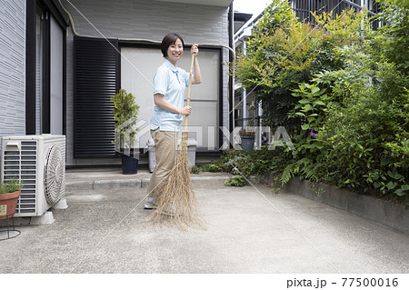駐車場の掃き掃除をするハウスクリーニング の女性 77500016