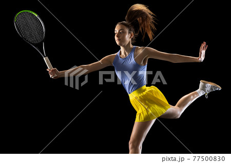 Young caucasian woman playing tennis isolated on black studio background in action and motion, sport concept Young caucasian woman playing tennis isolated on black studio background in action and motion, sport concept 77500830