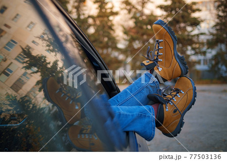 Woman feet on car door. Feet outside the window at sunset forest 77503136