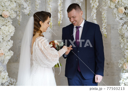exchange wedding rings.bride and groom in an arch of flowers at wedding ceremony exchange wedding rings.bride and groom in an arch of flowers at wedding ceremony 77503213