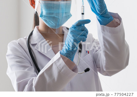バイアルからワクチンを引く医者 77504227