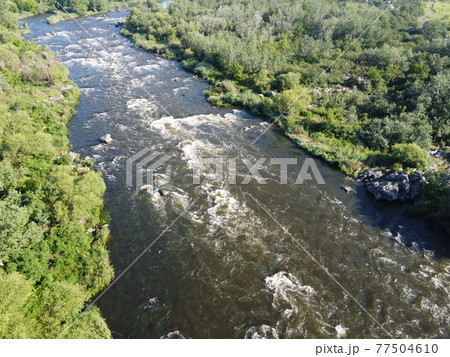 Picturesque river rapids on the Southern Bug. Rapid flow of the river over rocky terrain, landscape from a bird's eye view. Picturesque river rapids on the Southern Bug. Rapid flow of the river over rocky terrain, landscape from a bird's eye view. 77504610