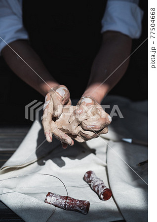 Female master kneads clay near wooden table on a pottery workshop 77504668