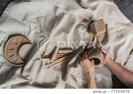 Top view of female hands sculpting clay vase. Pottery workshop. Hobby Top view of female hands sculpting clay vase. Pottery workshop. Hobby 77504676
