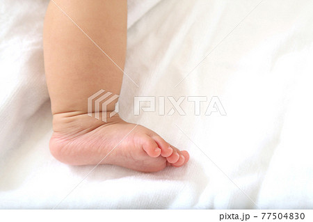 白シーツを背景にした新生児の片足のアップの写真素材