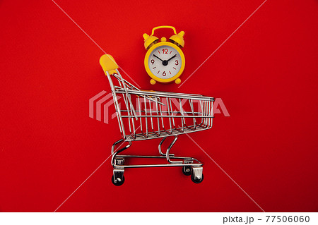 Shopping cart and yellow alarm clock isolated on red 77506060