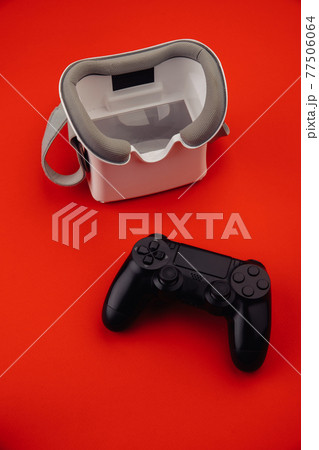 VR virtual reality glasses with gamepad on red background. Vertical image 77506064