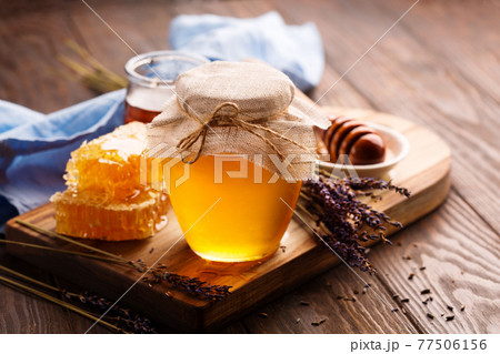 Jar of liquid honey with honeycomb and bunch of dry lavender Jar of liquid honey with honeycomb and bunch of dry lavender 77506156