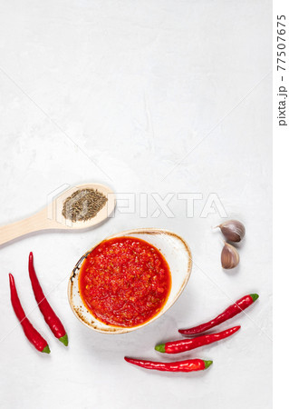 Hot chili pepper sauce paste harissa. Adjika on a white background. Traditional Tunisia, Georgian and Arabic cuisine. Homemade rose harissa in a bowl. 77507675