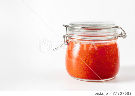 Hot chili pepper sauce paste harissa. Adjika. Traditional Tunisia, Georgian and Arabic cuisine. Homemade rose harissa in a glass jar. 77507683