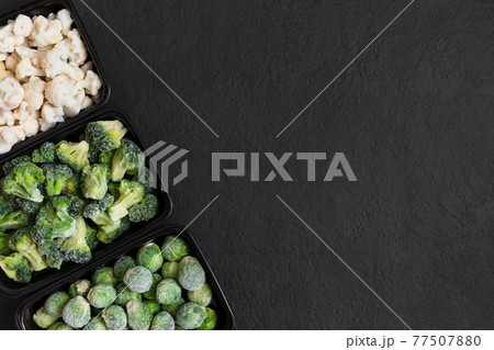 Frame of frozen vegetables in containers on a black background. Cabbage mix. View from above. Copy space. Frame of frozen vegetables in containers on a black background. Cabbage mix. View from above. Copy space. 77507880
