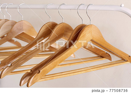 Empty wooden clothes hangers on aluminum rail 77508736