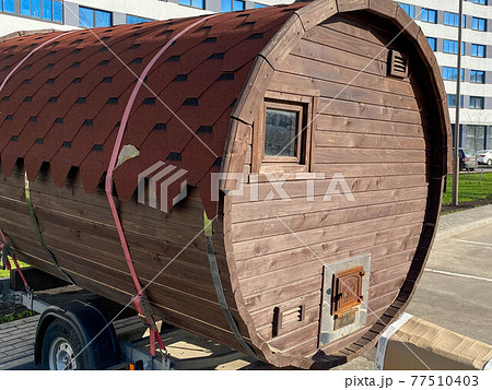 A large round mobile unusual bath or sauna in the form of a trailer for a car in the courtyard of the house for parking 77510403