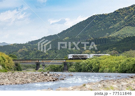 新緑の山間の川に架かる鉄橋を渡る日南線特急「海幸山幸」 77511846