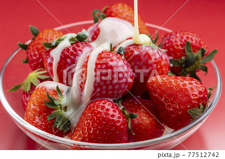 ガラスの器にのせた苺に練乳をかける ガラスの器にのせた苺に練乳をかける 77512742
