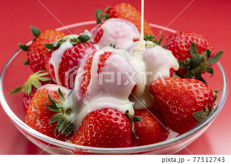 ガラスの器にのせた苺に練乳をかける 77512743