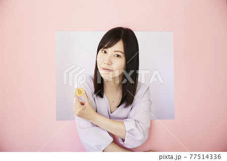 Woman holding Bitcoin on pastel pink colored Woman holding Bitcoin on pastel pink colored 77514336