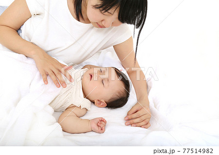 白背景で昼寝する赤ちゃんを見守るお母さん。育児、母性、愛情イメージ 白背景で昼寝する赤ちゃんを見守るお母さん。育児、母性、愛情イメージ 77514982