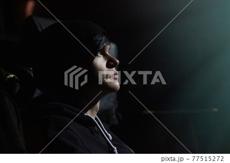 The side view of young black haired man with brow piercing in dark hall of concert or movie theater The side view of young black haired man with brow piercing in dark hall of concert or movie theater 77515272
