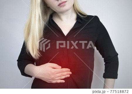 A woman holds on to his stomach. Pain in the abdominal cavity. The concept of diseases of the stomach and digestive system A woman holds on to his stomach. Pain in the abdominal cavity. The concept of diseases of the stomach and digestive system 77518872