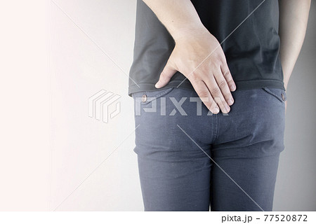 A man holds his hands to the ass feeling pain. Conversion of pain in the rectum, hemorrhoids and pain in the excretory system of the body. Frequent bowel movements. 77520872