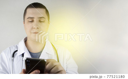 The doctor is holding a smartphone. Medical consultation by phone. Mobile app for healthcare providers The doctor is holding a smartphone. Medical consultation by phone. Mobile app for healthcare providers 77521180