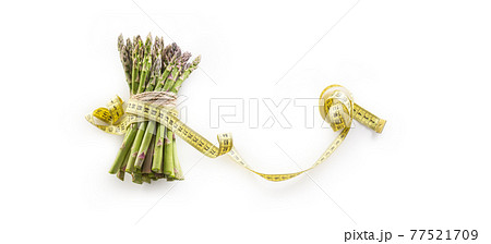 Fresh green asparagus with measure tape isolated on white background Fresh green asparagus with measure tape isolated on white background 77521709