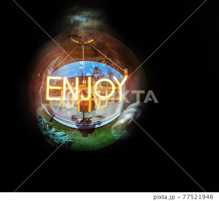 Edison's lamp with a glowing banner "Enjoy!" inside it on a dark background. Edison's lamp with a glowing banner "Enjoy!" inside it on a dark background. 77521946
