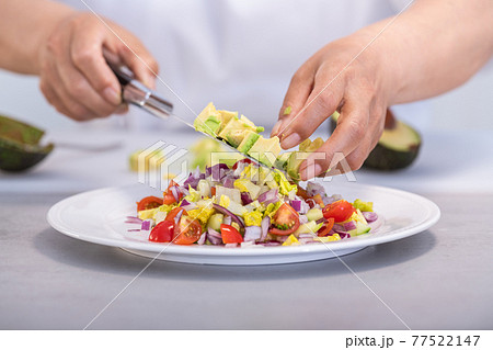 Putting avocado dice on a delicious salad Putting avocado dice on a delicious salad 77522147