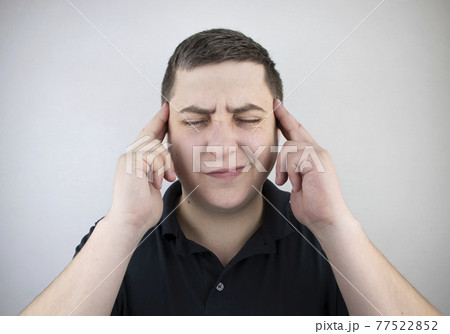 A man holds his head with his hands. Sensation of headache, migraine and dizziness. Headaches from stress or overwork 77522852