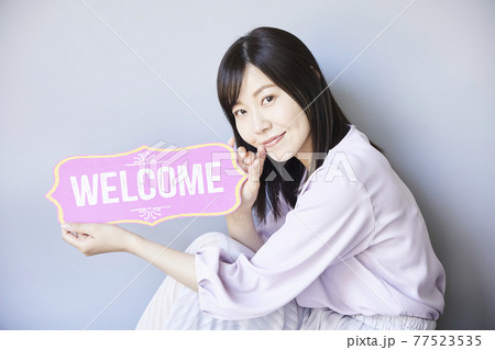 Woman has a board in her hand. welcome board Woman has a board in her hand. welcome board 77523535