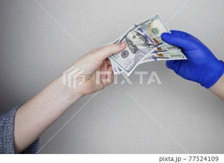 Patient's hand holds out money to the doctor. The concept of corruption in healthcare, bribery or paid medicine 77524109