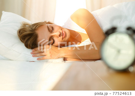 Beautiful blonde girl sleeping sweetly in sunny bedroom on a white bed. Holyday comfort and Rest concepts 77524613