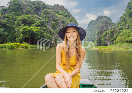 Woman tourist in boat on the lake Tam Coc, Ninh Binh, Viet nam. It's is UNESCO World Heritage Site, renowned for its boat cave tours. It's Halong Bay on land of Vietnam. Vietnam reopens borders after 77526525