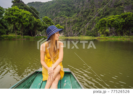 Woman tourist in boat on the lake Tam Coc, Ninh Binh, Viet nam. It's is UNESCO World Heritage Site, renowned for its boat cave tours. It's Halong Bay on land of Vietnam. Vietnam reopens borders after 77526526