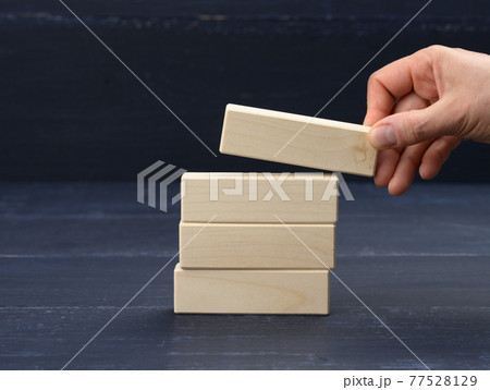 female hand puts wooden blocks on top of each other. Goal planning concept, new knowledge, strategy 77528129