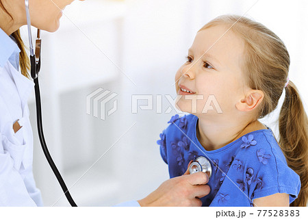 Doctor examining a little girl by stethoscope. Happy smiling child patient at usual medical inspection. Medicine and healthcare concepts Doctor examining a little girl by stethoscope. Happy smiling child patient at usual medical inspection. Medicine and healthcare concepts 77528383