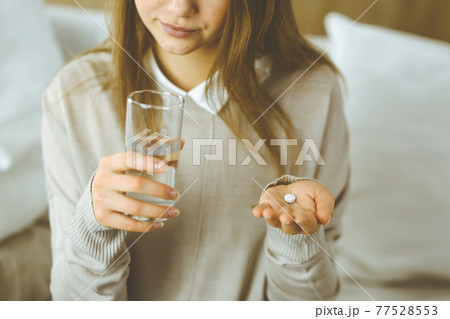 Close-up woman holding pills time to take medications, cure for headache, high blood pressure or cholesterol level remedy pain killer drugs. Stay at home concept during Coronavirus pandemic and self Close-up woman holding pills time to take medications, cure for headache, high blood pressure or cholesterol level remedy pain killer drugs. Stay at home concept during Coronavirus pandemic and self 77528553