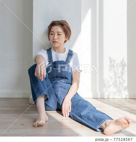 ジェンダーレス　LGBT 男の子みたいな女の子　オーバーオールを着て床に座る女性　正方形 77528567