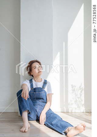 ジェンダーレス Lgbt 男の子みたいな女の子 オーバーオールを着て床に座る女性の写真素材