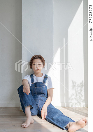ジェンダーレス　LGBT 男の子みたいな女の子　オーバーオールを着て床に座る女性 77528573