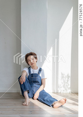 ジェンダーレス　LGBT 男の子みたいな女の子　オーバーオールを着て床に座る女性 77528576