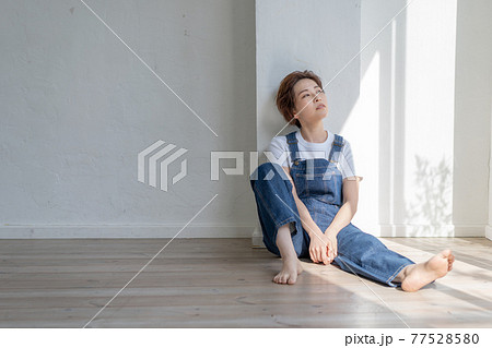 ジェンダーレス　LGBT 男の子みたいな女の子　オーバーオールを着て床に座る女性 77528580