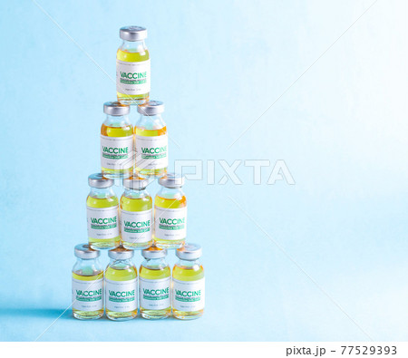 Vials of coronavirus vaccine doses are arranged in a pyramid on a blue background. Vaccine research and development concept covid-19, copy space for text Vials of coronavirus vaccine doses are arranged in a pyramid on a blue background. Vaccine research and development concept covid-19, copy space for text 77529393